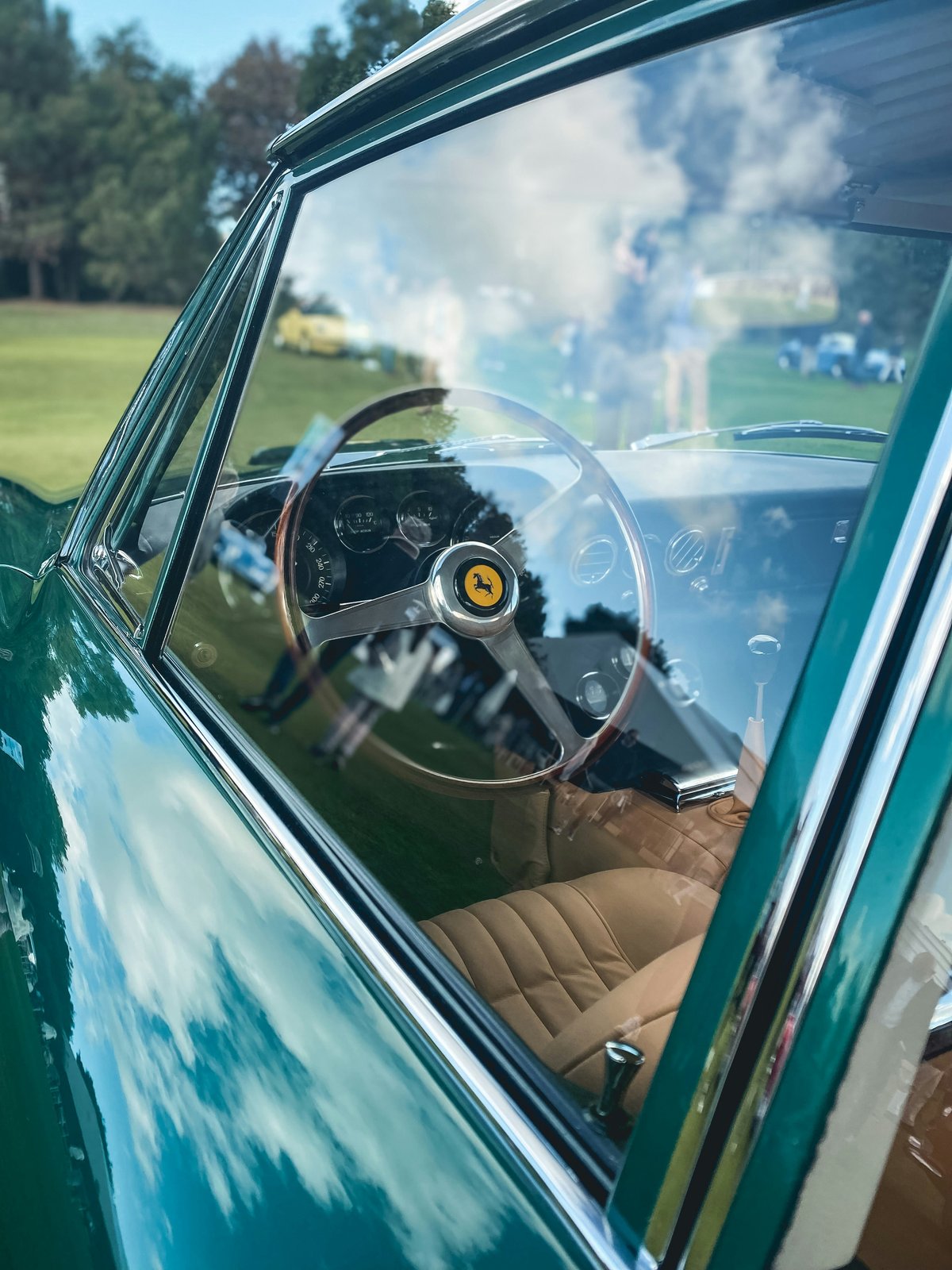 The steering wheel and dashboard of a vintage Ferrari seen through the driver's window
